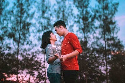 Young couple kissing against trees