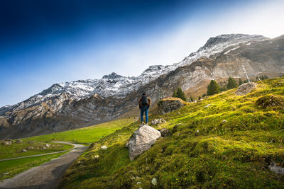 Rear view of man standing on rock against mountain