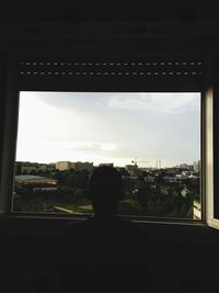 Rear view of silhouette man looking through window