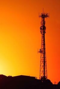 Silhouette of communications tower against sky during sunset