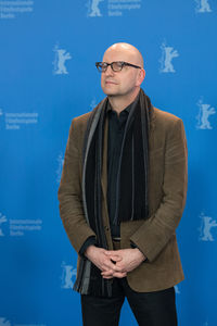 Portrait of man wearing hat standing against blue wall