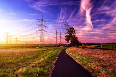 Road amidst field against sky during sunset
