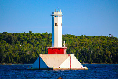 Lighthouse by sea against sky