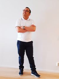 Full length portrait of young man standing against wall