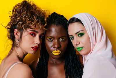 Portrait of women sitting against yellow background