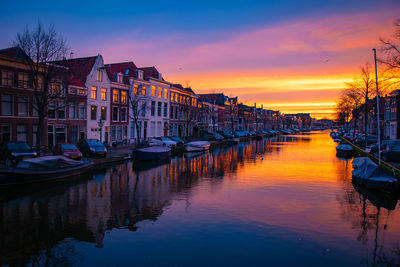Boats moored in canal against sky during sunset