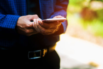 Midsection of man using mobile phone