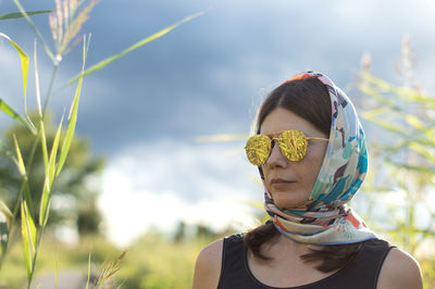 Woman wearing sunglasses and scarf against plants