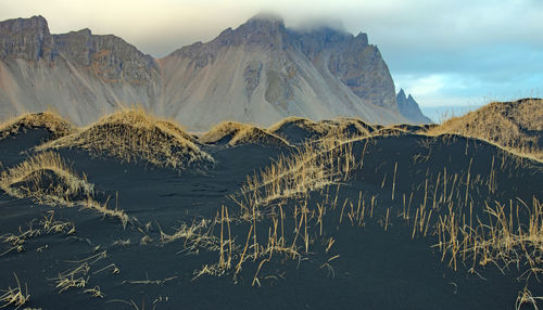 The peaks of mount vestrahorn, with vertiginous cliffs, are just about visible through low clouds. 
