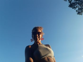 Portrait of young woman against clear blue sky