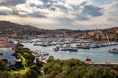 Boats moored in sea by cityscape against sky