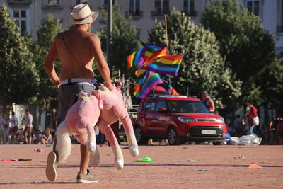 Full length of shirtless gay man holding stuff toy