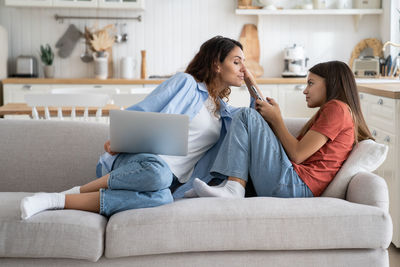 Friends using phone while sitting on sofa at home