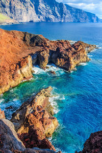 Scenic view of sea and rocks against blue sky