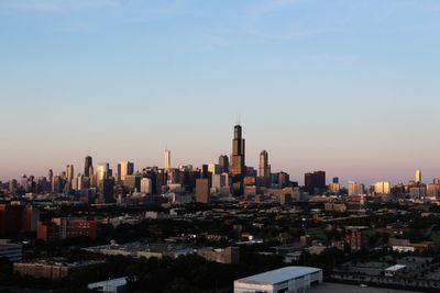 Modern buildings in city against sky during sunset