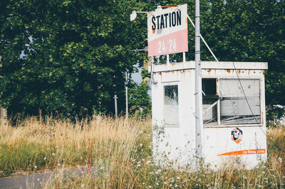 Text on old sign board at fuel pump against trees