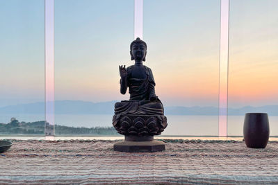 Statue of cross against sky during sunset