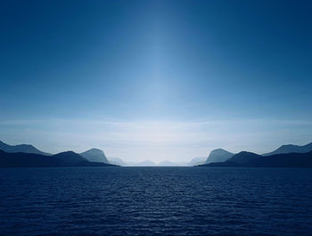 Into the wild, horizon over the sea, mountains and islands, luminous blue sky