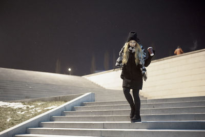 Woman walking on staircase in city at night