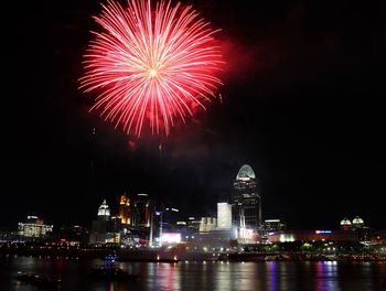 Low angle view of firework display over river at night