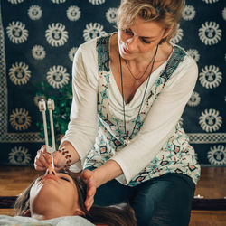 Therapist holding equipment on head of young woman at spa