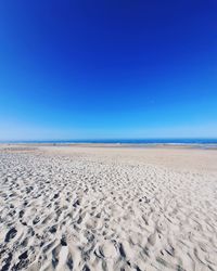 Scenic view of beach against clear blue sky