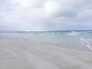 Scenic view of beach against cloudy sky