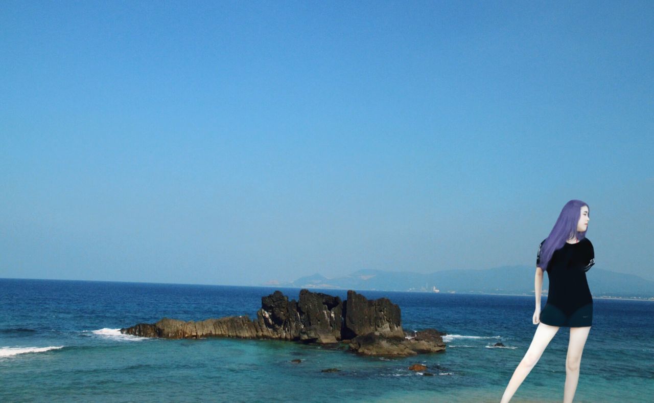 sea, water, one person, sky, rock - object, clear sky, rock, leisure activity, beauty in nature, blue, real people, lifestyles, copy space, standing, scenics - nature, solid, horizon over water, young adult, tranquility, outdoors, hairstyle