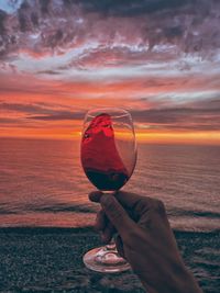 Man holding sunglasses in sea at sunset