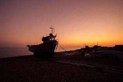 Scenic view of boat moored on shore at sunset