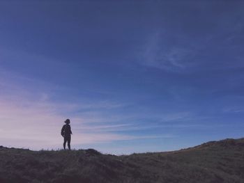 Low angle view of silhouette woman standing on mountain against sky