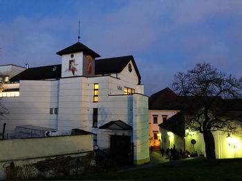 Houses by illuminated building against sky at night