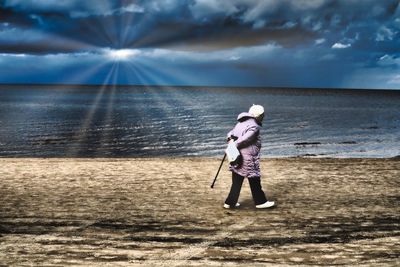 Full length of boy standing on beach against sky