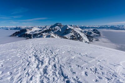 Scenic view of snowcapped mountains against blue sky