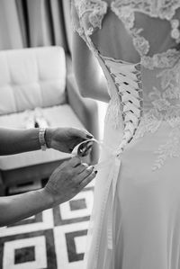 Midsection of woman helping bride in getting dressed