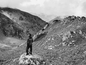 Rear view of man standing on mountain against sky