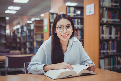 Portrait of a young woman sitting on book