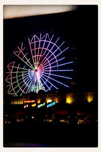 Low angle view of illuminated ferris wheel at night