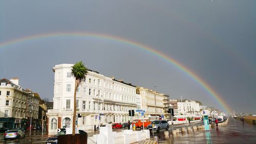 Rainbow over city against sky