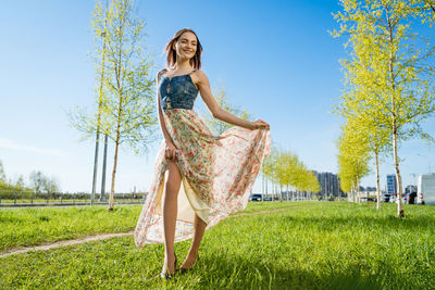 Portrait happy beautiful young woman relaxing in park in long dress. joyful