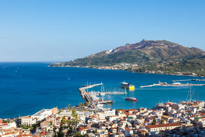 Aerial view of cityscape by sea against blue sky