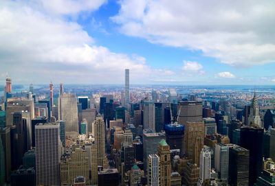 Aerial view of buildings in city against cloudy sky