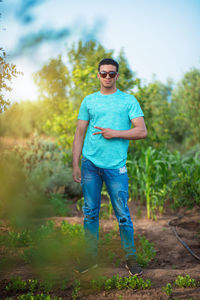 Portrait of young man wearing sunglasses standing on field