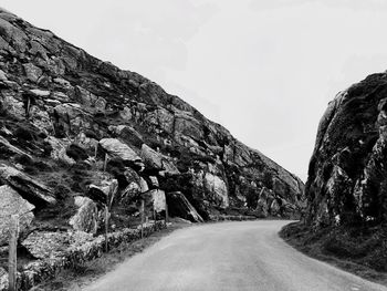 Road amidst rocky mountains against clear sky