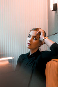 Portrait of young woman against wall at home