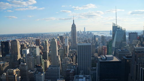 Aerial view of buildings in city against cloudy sky