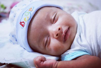 Close-up of baby girl sleeping on bed