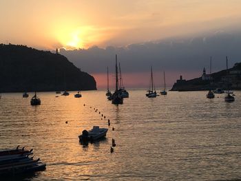 Sailboats moored on sea against sky during sunset