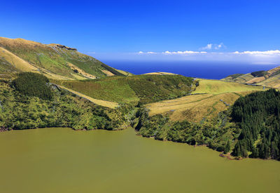 Scenic view of river by mountains against blue sky