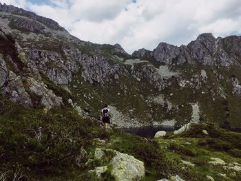 People on rocks by mountains against sky